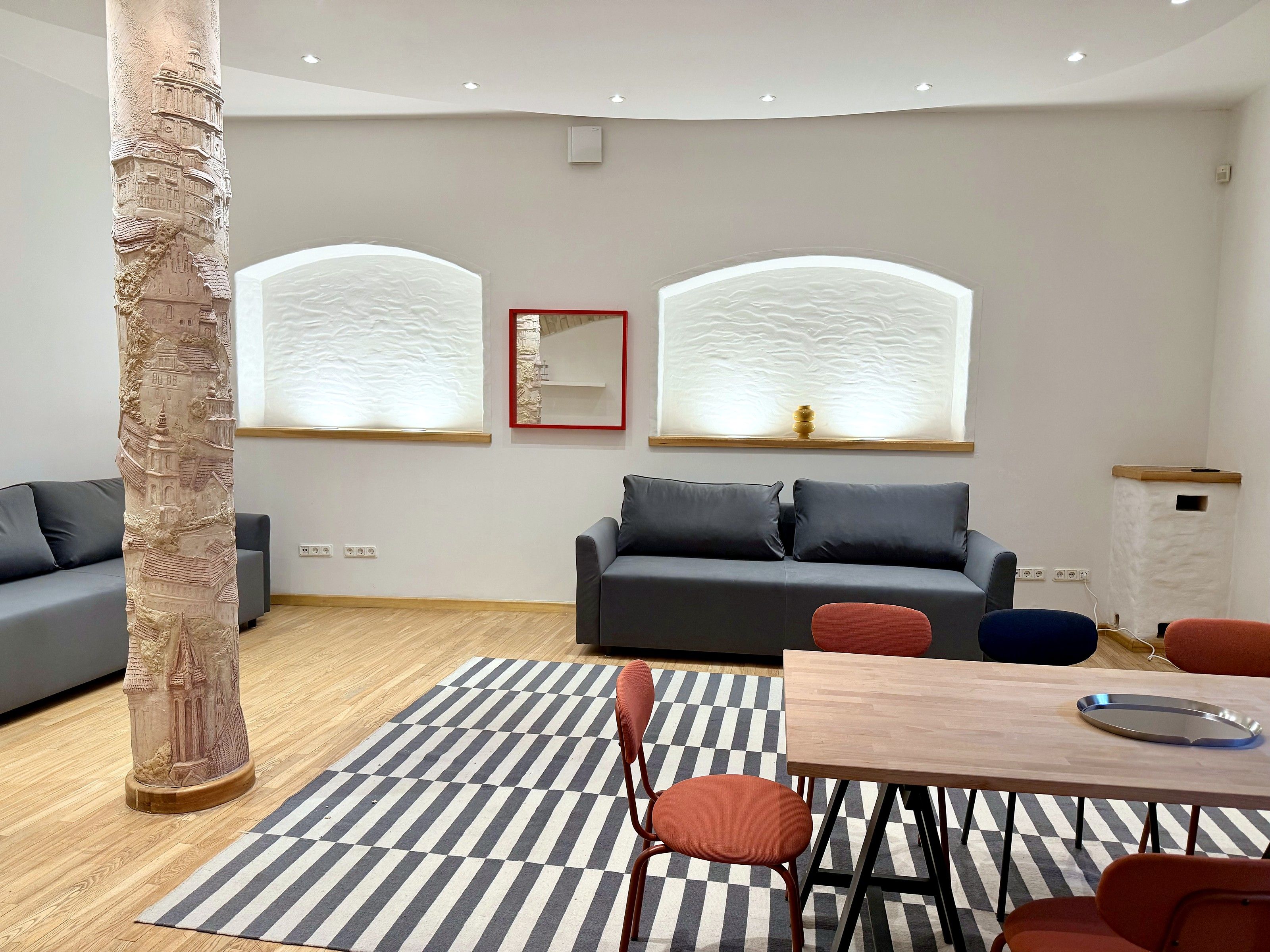 A modern living room with a sofa, a dining table, and a patterned rug.
