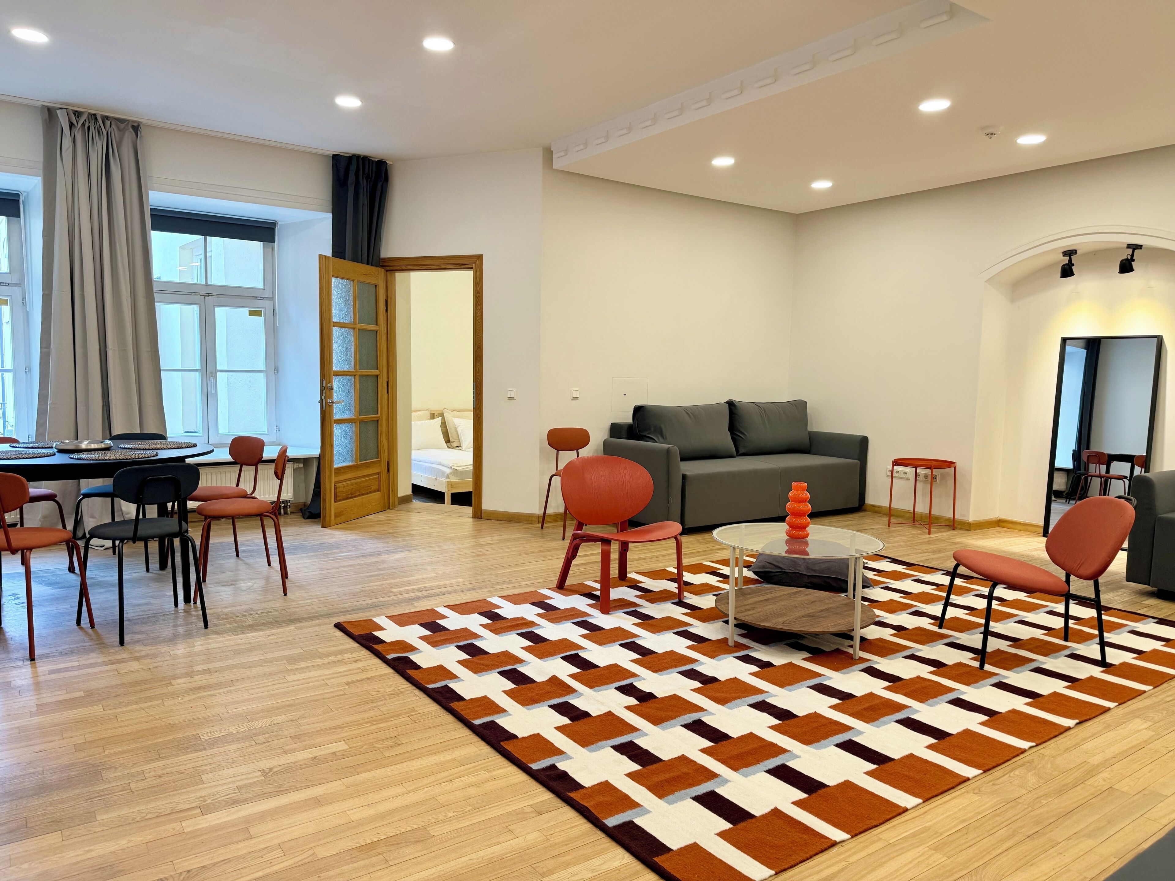 Ein modernes Wohnzimmer mit einer Couch, Sesseln, einem Couchtisch und einem gemusterten Teppich.