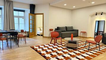 Ein modernes Wohnzimmer mit einer Couch, Sesseln, einem Couchtisch und einem gemusterten Teppich.