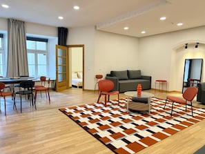 A modern living room with a sofa, chairs, a coffee table, and a patterned rug. - Zema11 Old Town Space (Vilnius)