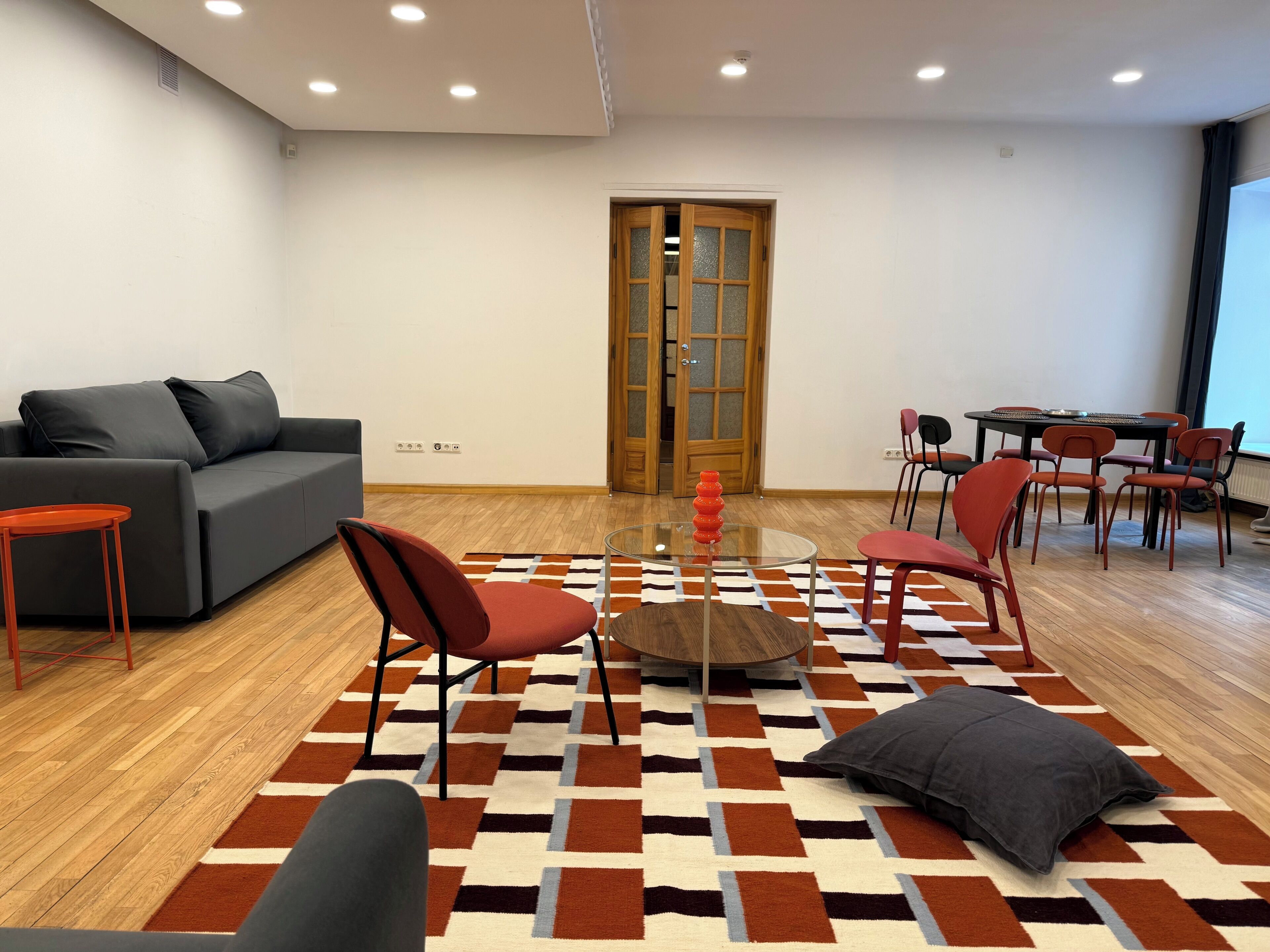 Un saló modern amb un sofà, cadires, una taula de centre i una catifes amb disseny.