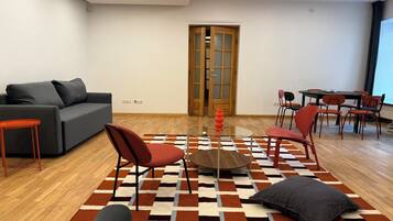 Un saló modern amb un sofà, cadires, una taula de centre i una catifes amb disseny.