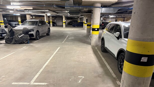 Un aparcamiento de varios niveles con pilares de hormigón y plazas delimitadas.