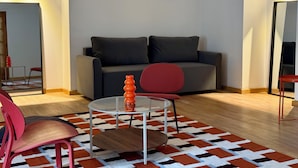 Una sala moderna con un sofá, una mesa de vidrio y una silla roja.