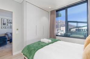 Ein Hotelzimmer mit Bett, Blick auf eine Stadtlandschaft und eine Brücke, einem Kleiderschrank und einer Sitzecke mit Sofa und Sesseln.