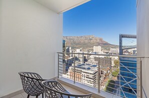 Ein Balkon mit zwei Stühlen und Blick auf eine Stadtlandschaft und ein Gebirge.