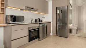 A modern kitchen with built-in appliances, including a microwave, oven, dishwasher, and refrigerator. - Designer Green Point Stay | Pool and Balcony (Cape Town)