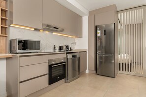 Eine moderne Küche mit integrierten Geräten, darunter Mikrowelle, Backofen, Geschirrspüler und Kühlschrank.
