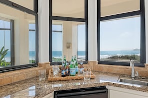 Eine Küche mit Granit Arbeitsplatte, einem integrierten Geschirrspüler und Meerblick durch große Fenster.