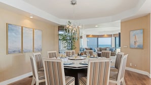 A dining area with a round table, striped chairs, and a chandelier. - Padaro by the Sea - Exclusive Beachfront Estate (Carpinteria)