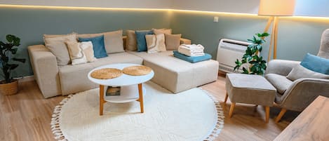 A cozy living room with a sectional sofa, a small round table, and a lamp.