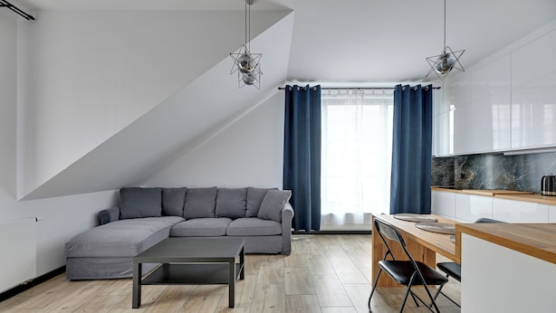A modern living space with a sectional sofa, a dining table with chairs, and a kitchen area with a marble countertop. - Botanica Jelitkowo Morze i Slow (Gdańsk)