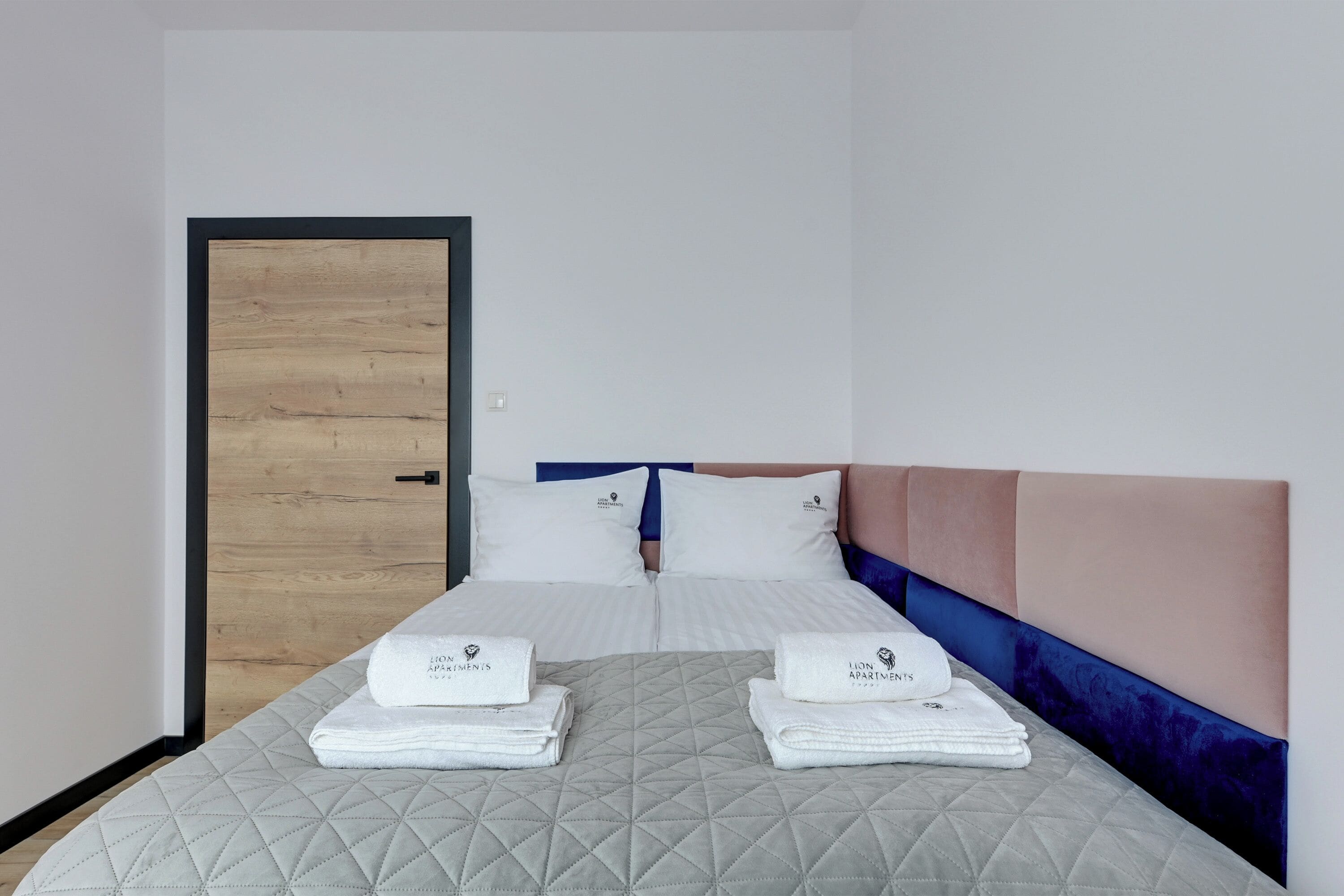 Ein Hotelzimmer mit einem Bett, zwei Kissen, einem Kopfteil und einer Tür.