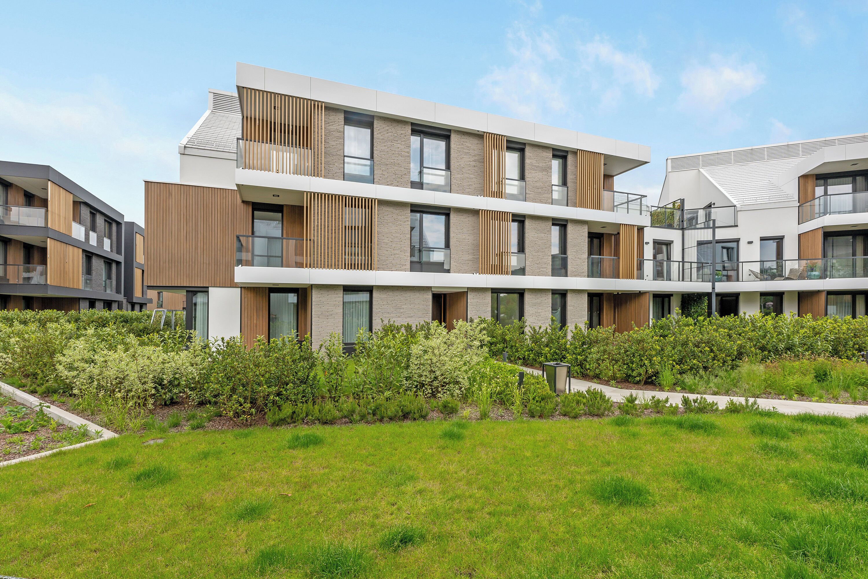 Ein modernes Mehrfamilienhaus mit Balkonen und einem gepflegten Garten.