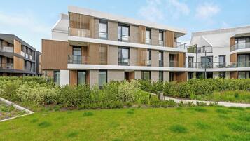 A modern multi-story residential building with balconies and a well-maintained garden.