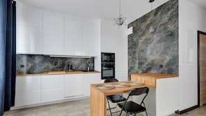 A modern kitchen with white cabinets, a wooden countertop, a built-in oven, and a marble backsplash. - Botanica Jelitkowo Morze i Slow (Gdańsk)
