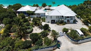 A beachfront property with multiple buildings, a swimming pool, and a clear view of the ocean.