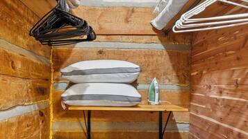 A small, wooden room with a wooden bench, a hanging clothes rack, and a storage bin.