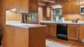 A wooden interior with a kitchen area, including a central island, cabinets, and a microwave.