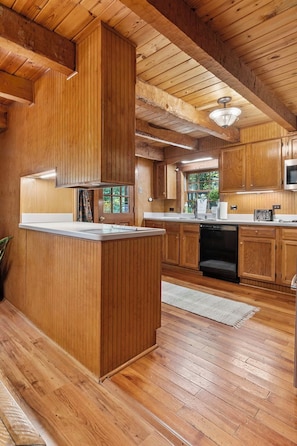 Un interior de madera con cocina, que incluye una isla central, armarios y un microondas.