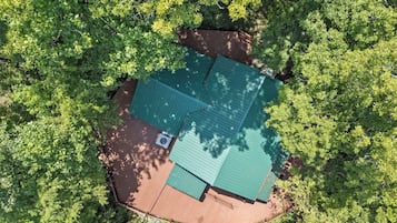 A house with a green roof surrounded by dense green foliage.