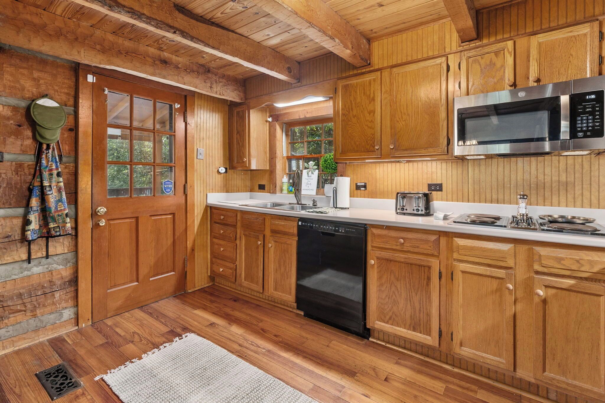 Una cocina de madera con lavavajillas integrado, microondas y tostadora.
