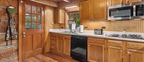 Una cocina de madera con lavavajillas integrado, microondas y tostadora.