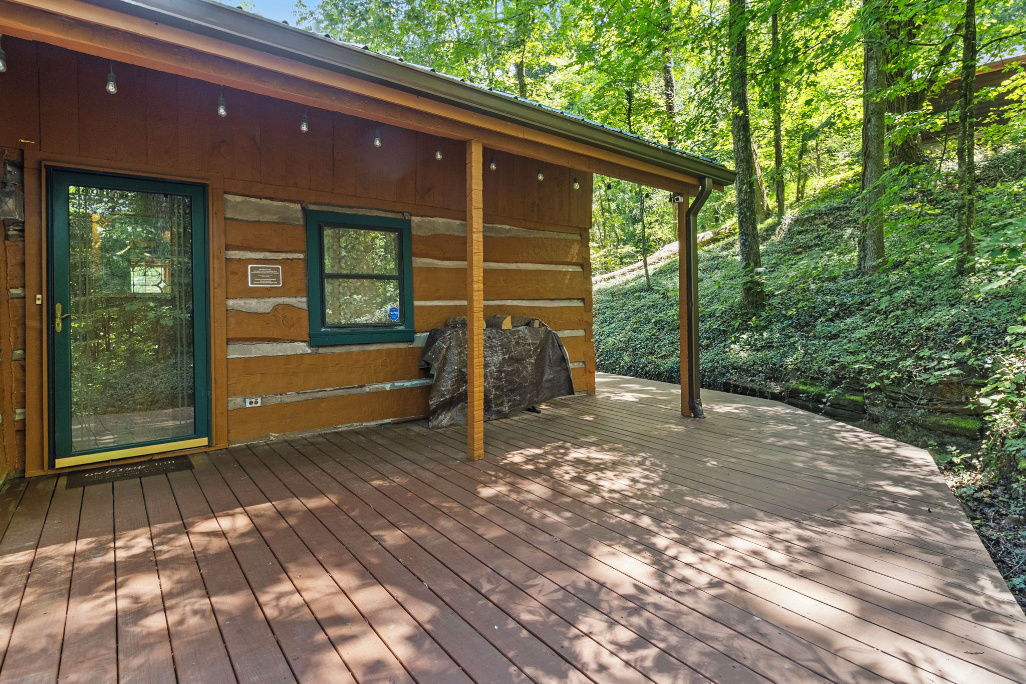 A wooden cabin with a covered deck and a glass door.