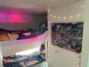 A room with a bunk bed, a poster of Air France, and string lights. - 'La Saucisserie' Walnut - 
Cozy cottage great for a small family or couple (Saint-Pierre-de-Frugie)