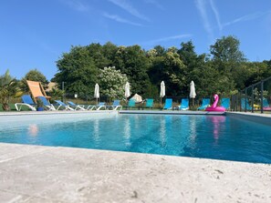 A swimming pool with lounge chairs and umbrellas, surrounded by trees. - La Saucisserie - Walnut (Saint-Pierre-de-Frugie)