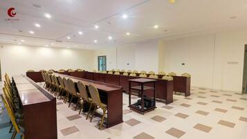 A conference room with a long table and chairs, a projector, and a door in the background.