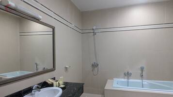 A bathroom with a bathtub, a shower, a sink, and a mirror.