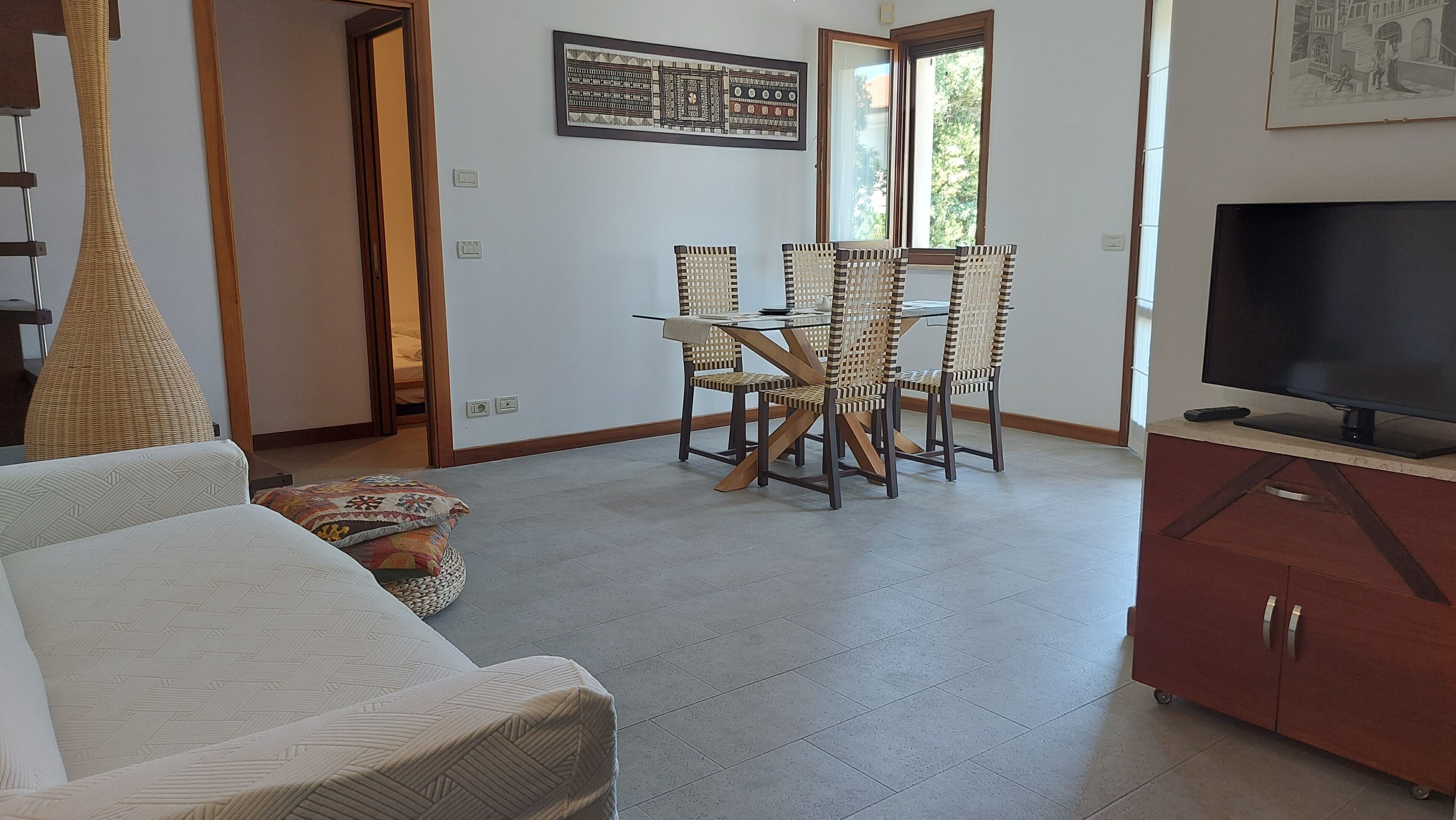 A living room with a sofa, a dining table with chairs, a television, and a cabinet.