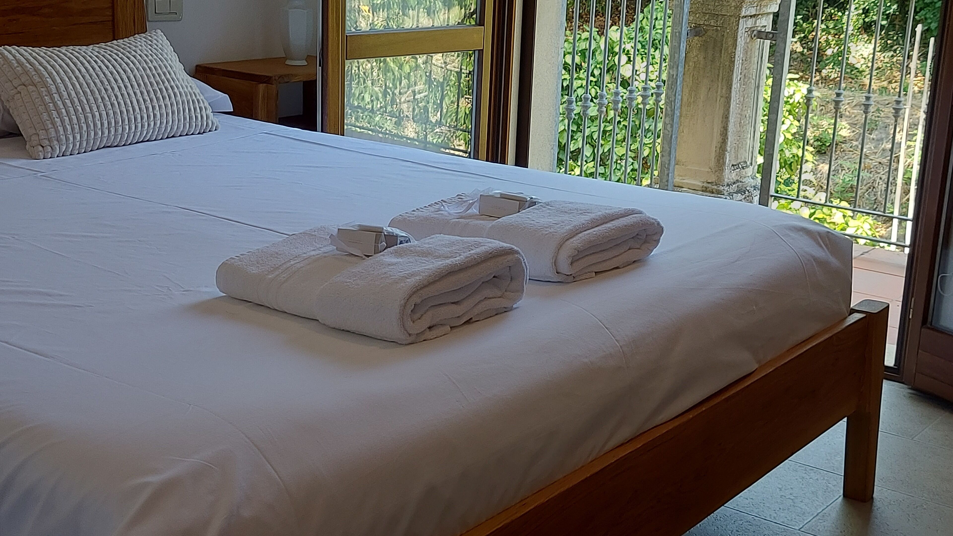 Un lit avec du linge de lit blanc et deux serviettes pliées.