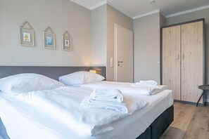 Ein Hotelzimmer mit zwei Betten, einem Holzschrank und drei gerahmten Bildern an der Wand.