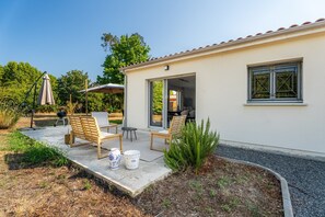 A patio area with outdoor furniture, a barbecue grill, and a small garden. - L'air du Médoc - Jolie maison pour 6 avec jardin (Cussac-Fort-Médoc)