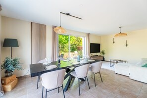 Ein Essbereich mit einem Tisch für vier Personen, Stühlen, einem Fernseher und einem Sofa.