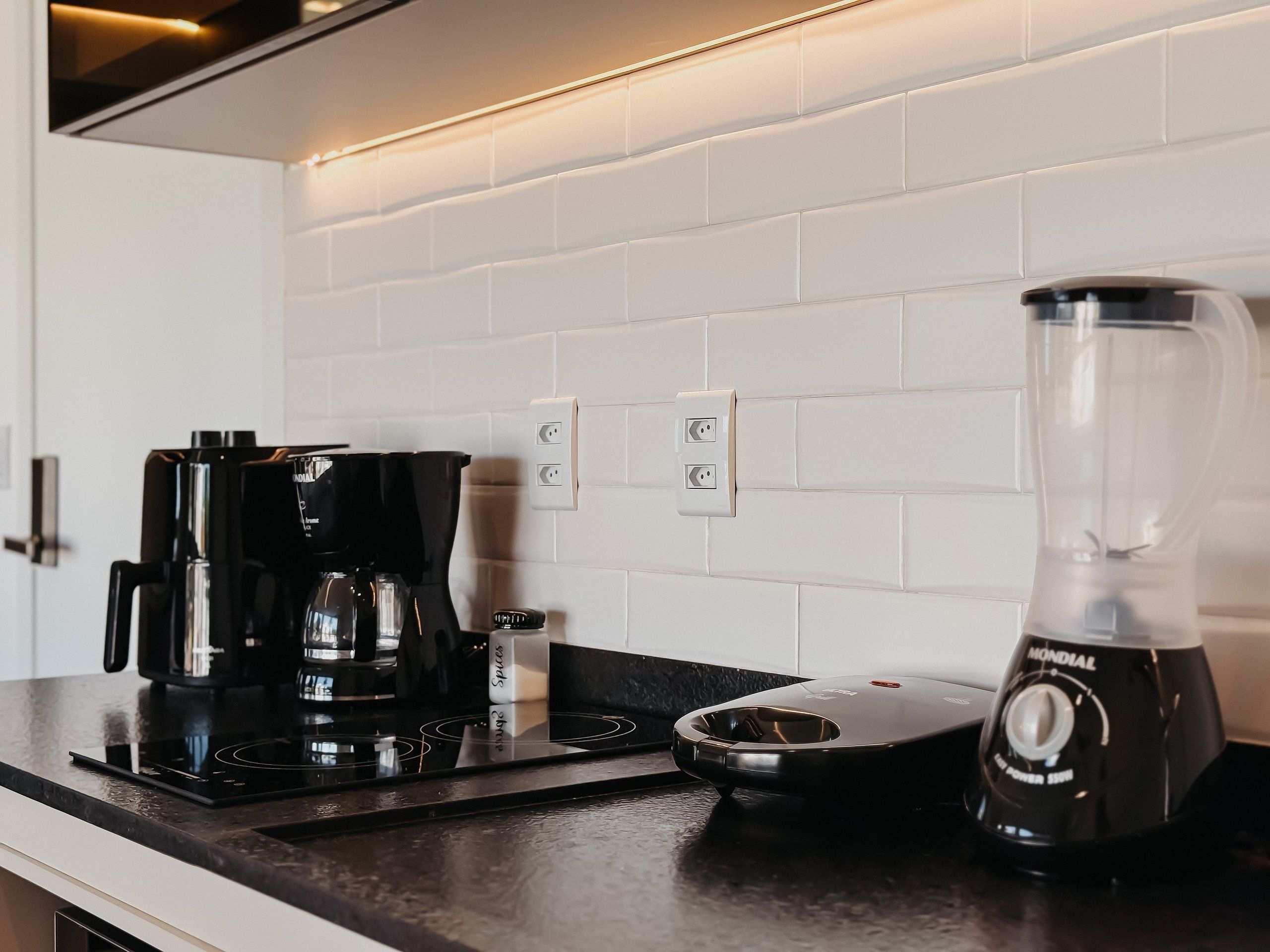 Een keuken met een koffiezetapparaat, een blender en een kookplaat.