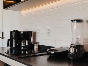A kitchen with a coffee maker, a blender, and a stovetop.