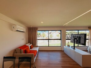 Una sala de estar moderna con un sofá, un televisor y un ventanal grande.