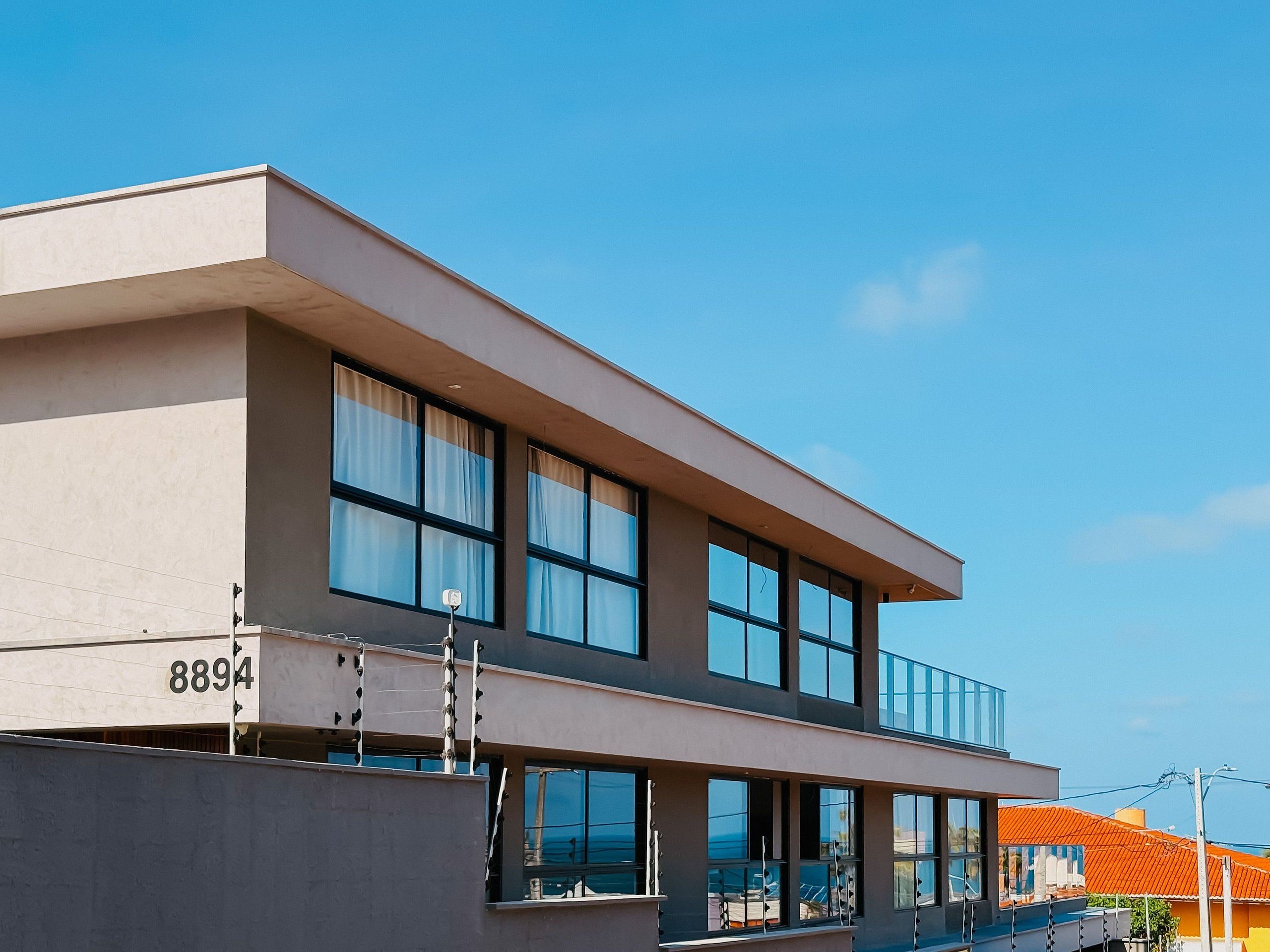 Een modern gebouw met twee verdiepingen, grote ramen en een plat dak.