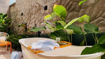 A spa area with a bathtub, towels, and a stone wall.