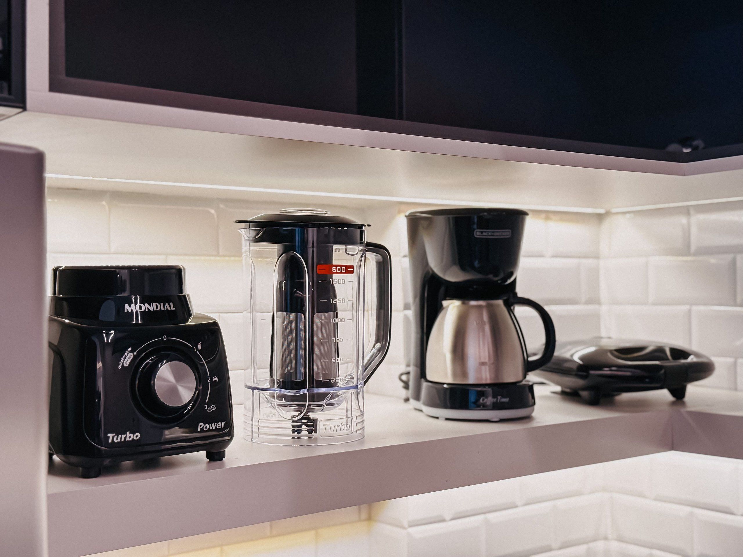 Una encimera de cocina con una cafetera, una licuadora y un molinillo de café.