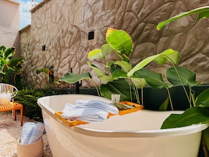 Un espacio de spa con bañera, toallas y una pared de piedra.