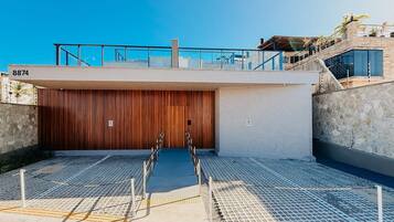 A modern building with a large wooden door, a balcony with railings, and a stone wall.