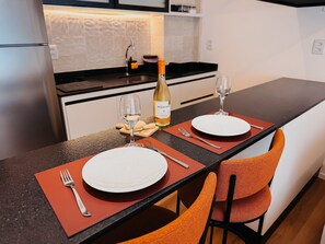 Comedor con una mesa preparada para dos personas, incluyendo platos, cubiertos y vasos.