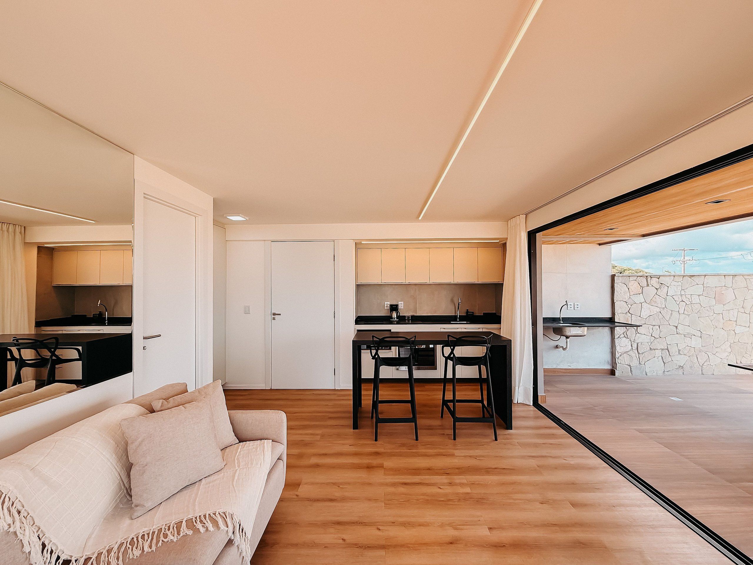A modern kitchen with a dining area, a sofa, and a view of the outdoors.