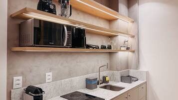 A modern kitchen with a built-in microwave, coffee maker, and a kettle on the countertop.