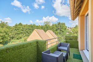 A balcony with wicker furniture, a clear view of the sky, and a well-maintained hedge. - Évasion Côte Fleurie - Proche Plage (Touques)