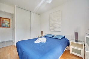 Et hotelværelse med en stor seng, et natbord, en vægmonteret kunstgenstand og en dør.